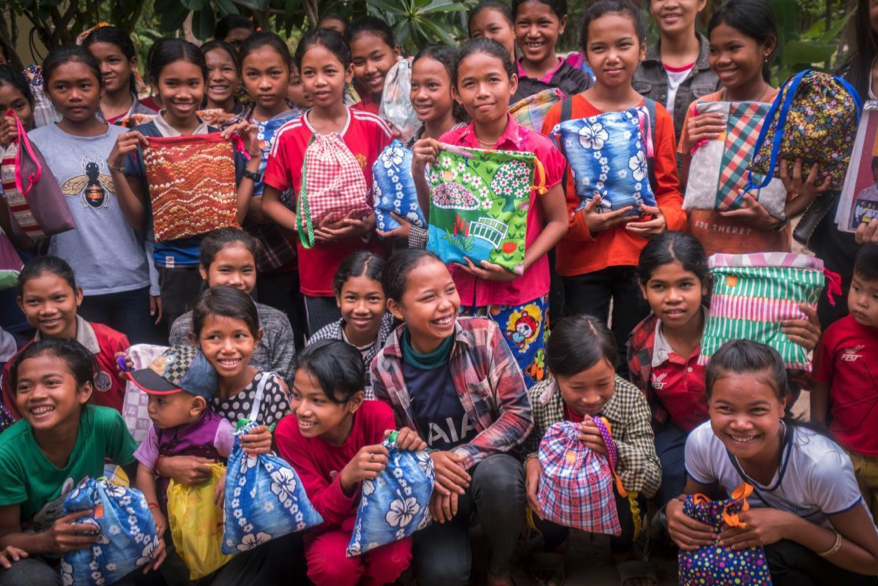 Children holding bags created by donated fabrics