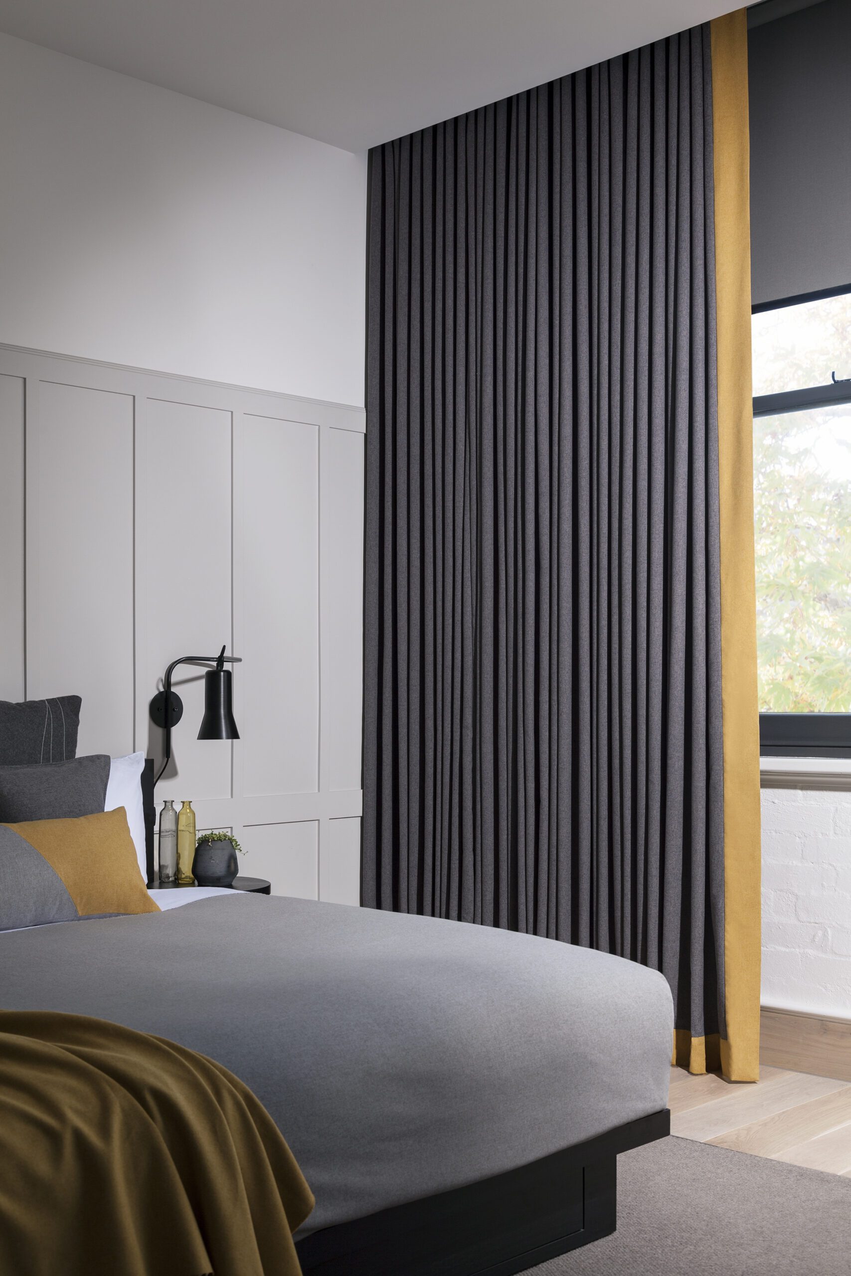 Charcoal wave-fold blockout curtains with mustard banding in a bedroom with grey and gold bedding